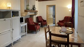 A dining area with a wooden table, chairs, and a television. There are two red upholstered chairs and a white cabinet with a television.