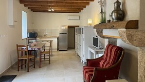 A kitchen with a dining area, a refrigerator, a TV, and a red chair.