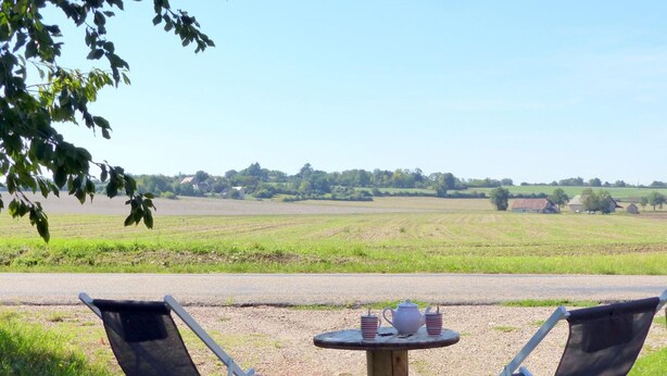 A table with two chairs and a teapot in a rural setting.