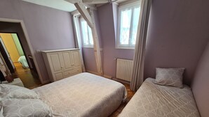 A bedroom with two beds, a wardrobe, a radiator, and a window with curtains. - Townhouse in Orléans, near Loire and center (Orléans)
