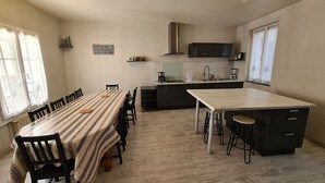 A spacious kitchen with a dining area, featuring a long table and chairs, a central island with stools, and modern appliances. - Townhouse in Orléans, near Loire and center (Orléans)