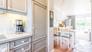 A modern kitchen with a coffee maker, a Siemens appliance, and a dining area with a table and chairs.