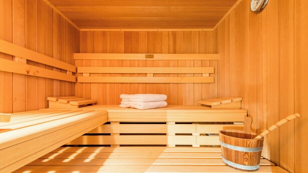 A wooden sauna with benches and a bucket.