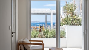 A balcony with a white pergola, a wooden chair, and a small round table. - Villa Santa Esmeralda Mykonos (Mykonos)