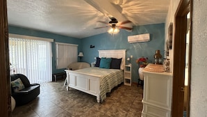 A bedroom with a bed, a chair, a nightstand, a lamp, and a ceiling fan. - Relaxing Coastal Treasure on the canal (Corpus Christi)