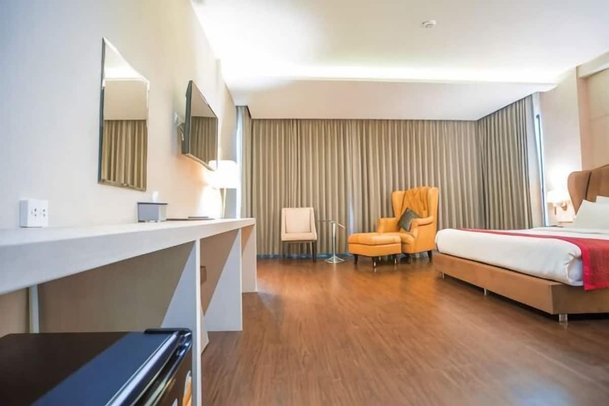 A hotel room with a bed, a desk, a chair, a lamp, and a large window.
