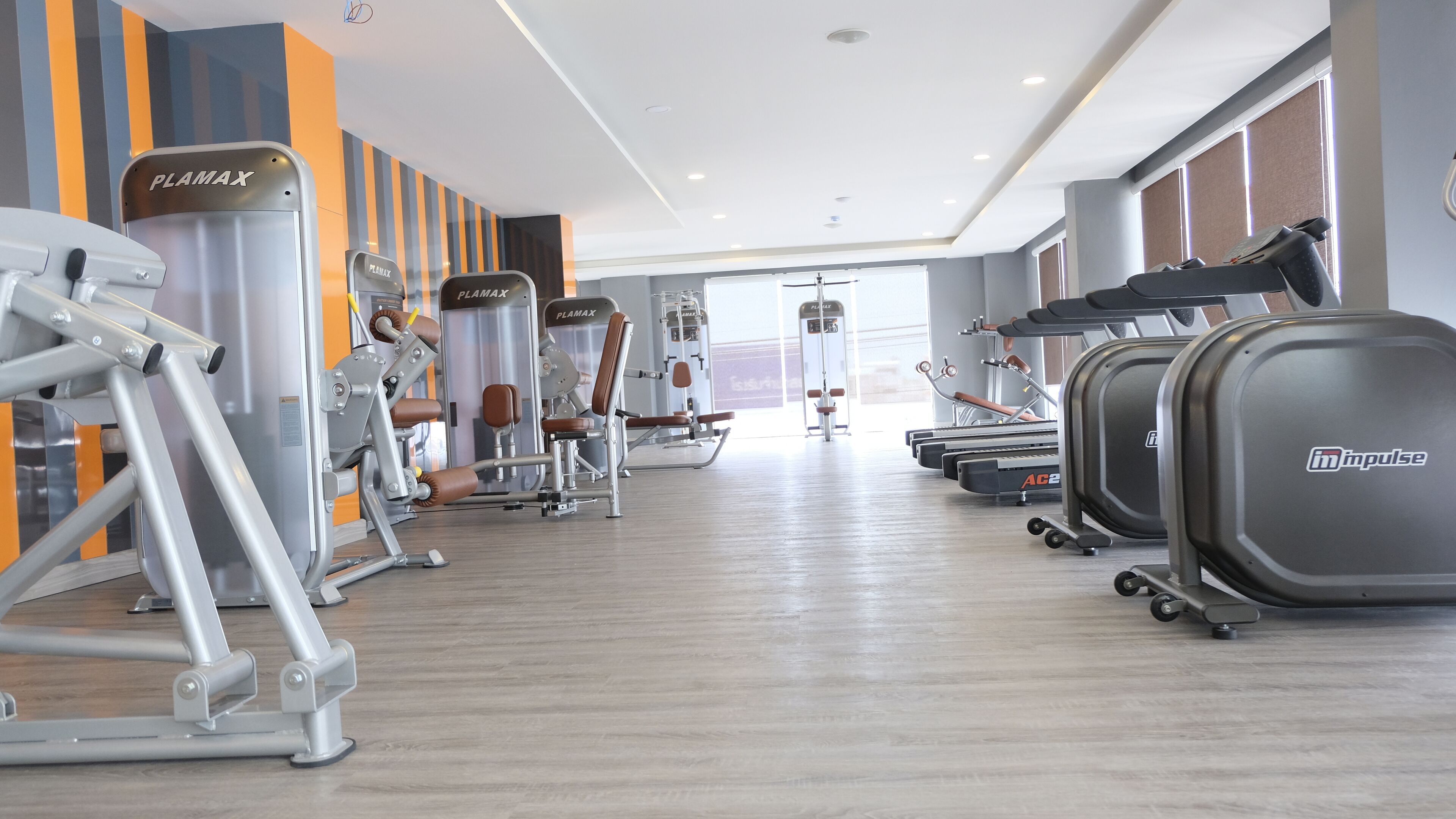 Ein Fitnessstudio mit unterschiedlichen Trainingsgeräten, darunter Kraftgeräte und Laufbänder.
