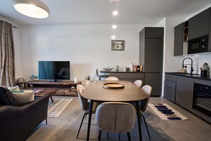Uma sala de estar moderna com televisão, sofá e área de refeições.