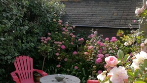 A wooden deck with a round table and four red chairs. - Manor house in Brittany, 20 metres from the beach, 1 minute walk (Plouescat)