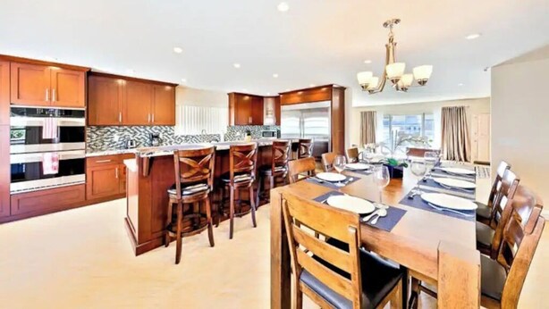 Una cocina moderna con armarios de madera, una isla central y un comedor con candelabro.