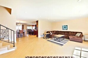 A spacious living area with a brown sectional sofa, a coffee table, and a patterned rug.