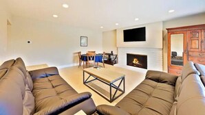 Una sala de estar con chimenea, sofás de cuero, una mesa de centro y un televisor de pantalla plana montado sobre la chimenea.
