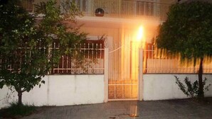 Un immeuble de deux étages doté d’une entrée fermée par un portail, d’un balcon et d’un petit jardin.