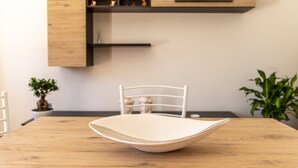 A dining table with a white bowl, a white chair, and a wooden cabinet with shelves. - Pet-Friendly Apartment 'I due ulivi' with view on the hills of Modica, Terrace & Wi-Fi (Modica)