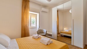 A hotel room with a bed, a chair, a wardrobe, and a window with curtains. - Pet-Friendly Apartment 'I due ulivi' with view on the hills of Modica, Terrace & Wi-Fi (Modica)