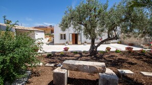 A white building with a tiled roof, a tree in the center, and potted plants around. - Pet-Friendly Apartment 'I due ulivi' with view on the hills of Modica, Terrace & Wi-Fi (Modica)