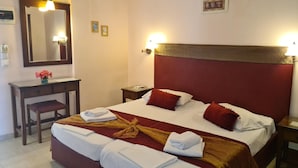 Une chambre d’hôtel équipée d’un lit, de tables de chevet, d’un bureau, d’un miroir et de lampes fixées au mur.