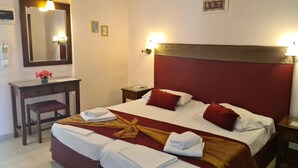 Habitación de hotel con cama, mesitas de noche, escritorio, espejo e iluminación en la pared.