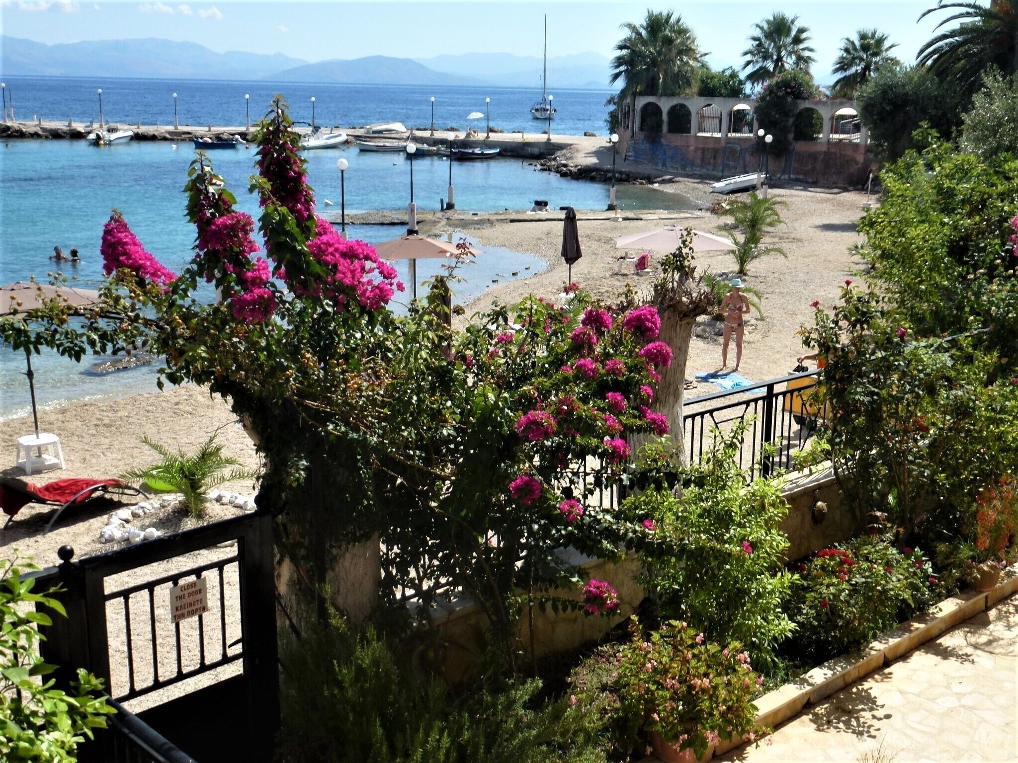 A coastal view with a beach, boats, and a building with arches.