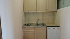 A compact kitchen with a sink, stove, and a small refrigerator.