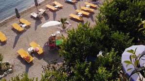 A beach with sun loungers, umbrellas, and a few people.