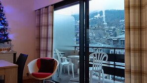 A modern apartment with a balcony, a dining area, and a Christmas tree.