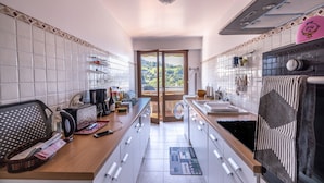 A kitchen with white cabinets, a wooden countertop, a coffee maker, and a view through a glass door.