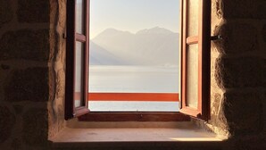 A stone-walled room with a window opening to a mountain view. - Private Stone House Next to the sea (Kotor)