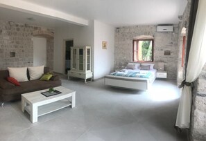 Un'ampia stanza con un letto, una poltrona e un tavolino da caffè bianco.