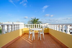 A balcony with a white table and chairs, a yellow wall, and a clear blue sky. - 'Villa Amador' with Sea View, Pool & Wi-Fi (L'Ampolla)