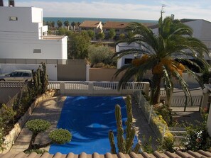 Zona residencial con piscina, palmeras y casas.