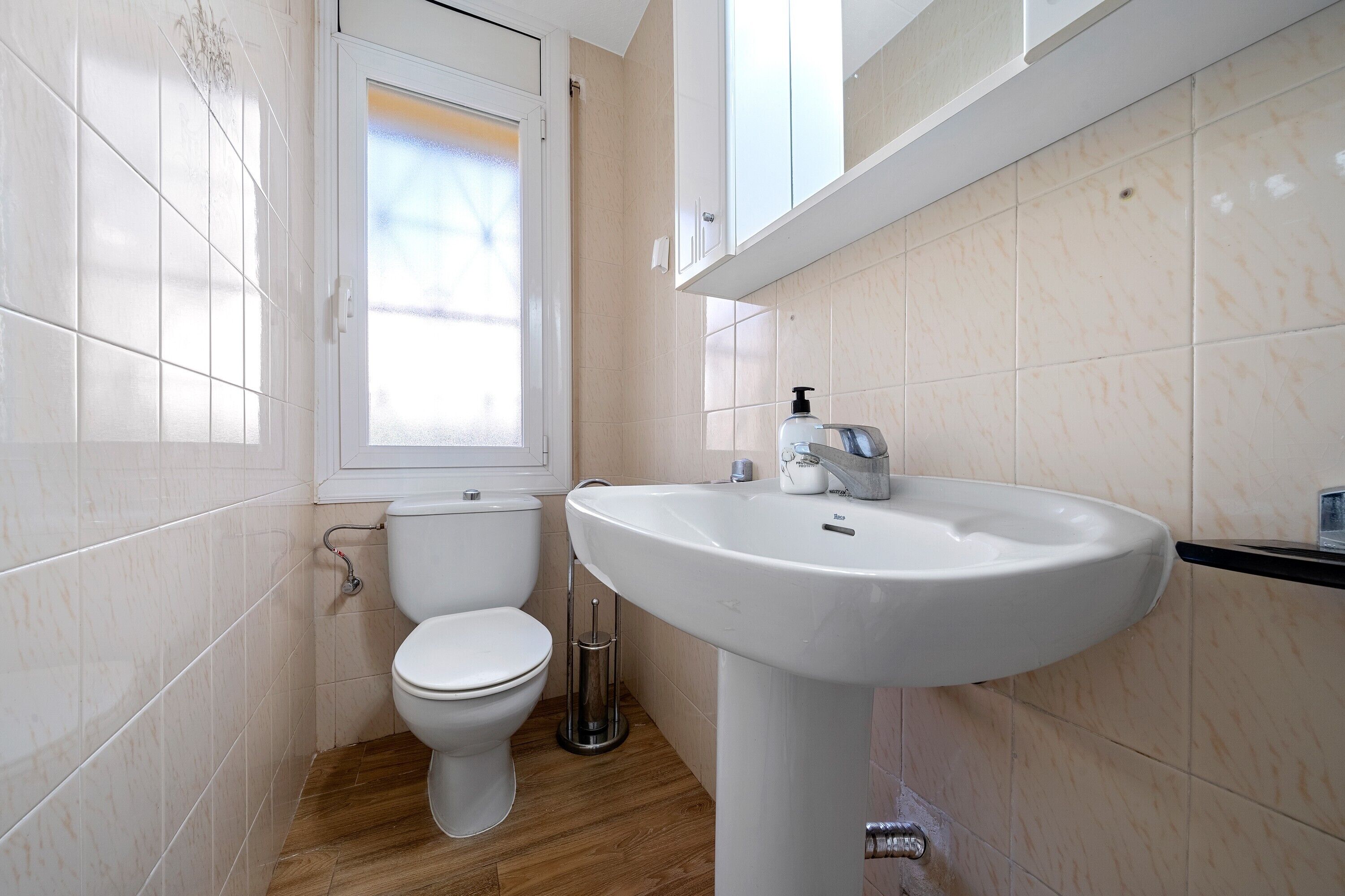 A bathroom with a toilet, a sink, and a window.