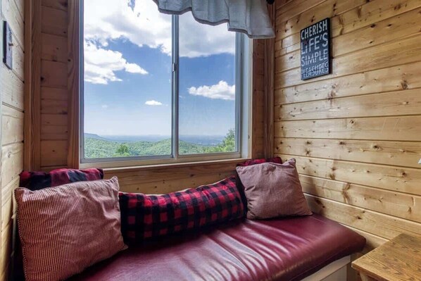A wooden cabin with a bench by a large window overlooking a scenic landscape. - Stone Crest Summit: Balcony w/Mountain Views, Spa & Pool by Beyond Expectations (Gatlinburg)