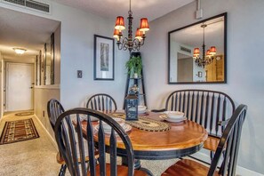 A dining room with a round wooden table, black chairs, a chandelier, and a mirror on the wall. - Gatlinburg Escape 2BR Condo with Mountain Views & Indoor Pool and Spa Access (Gatlinburg)