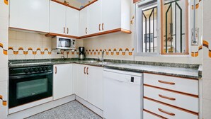 Een keuken met witte kastjes, een magnetron, een fornuis en een vaatwasser.