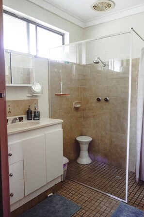 Een badkamer met een douche, toilet en wastafel.