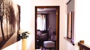 Ein Flur mit einem Holztisch, einer Blumenvase, einer Obstschale und einem großen Gemälde an der Wand.