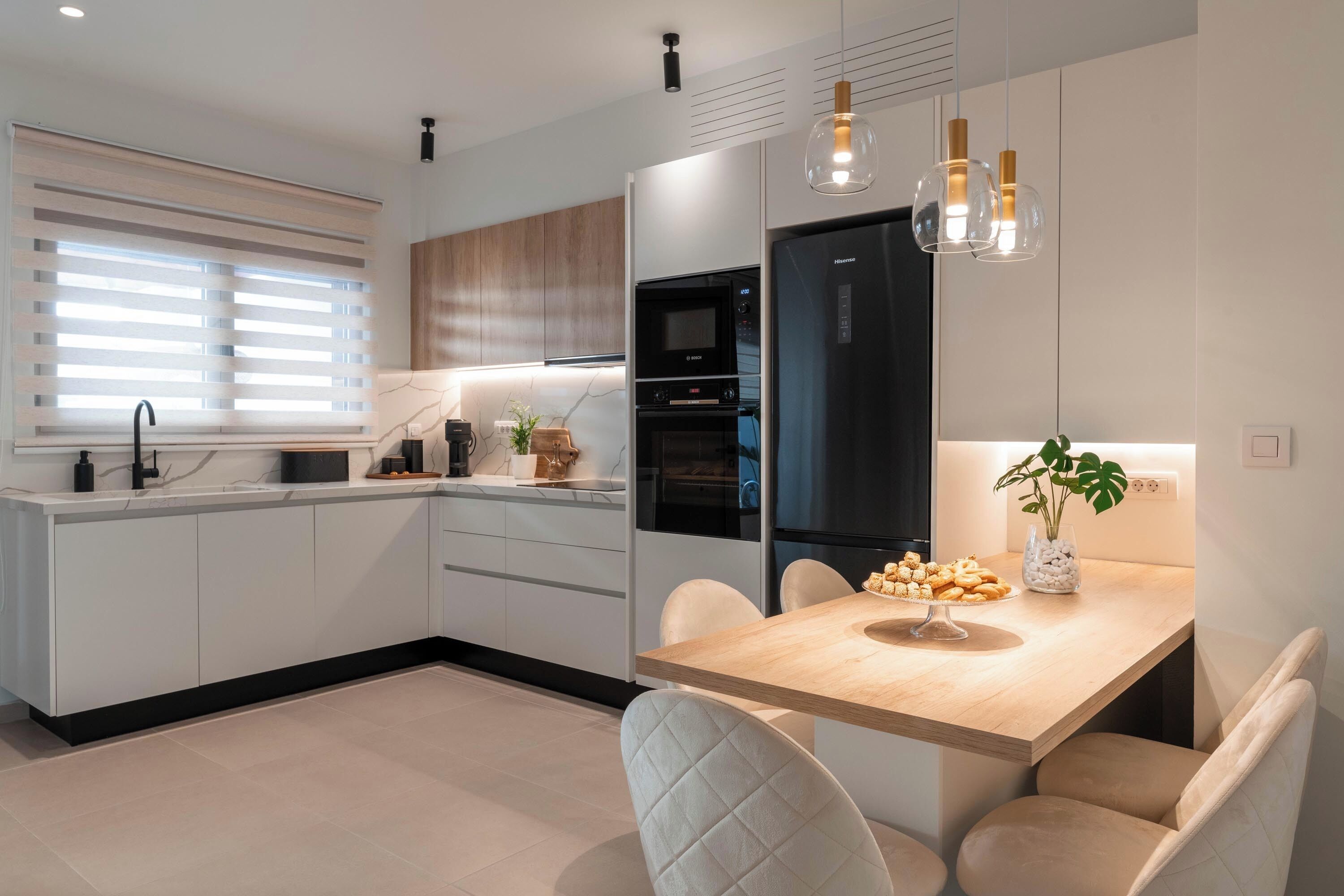 Een moderne keuken met een centraal eiland, ingebouwde apparatuur en hanglampen.