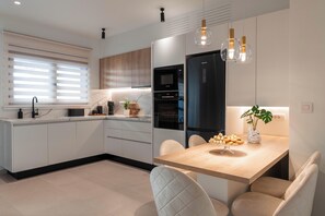 A modern kitchen with a central island, built-in appliances, and pendant lighting.