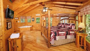 Une cabane en bois avec un lit à baldaquin, une baignoire en bois et un ventilateur de plafond.