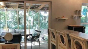 Una cocina con una mesa de madera, sillas y una encimera. Hay dos cuadros en la pared.