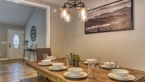 A dining area with a wooden table set for four, a chandelier, and a landscape painting on the wall. - Tranquility Hollow Private INDOOR POOL, WIFI, next to Dollywood (Sevierville)