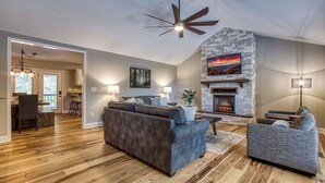A spacious living room with a stone fireplace, hardwood flooring, and modern furniture. - Tranquility Hollow Private INDOOR POOL, WIFI, next to Dollywood (Sevierville)