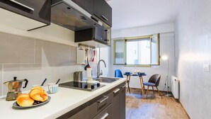 Une cuisine compacte équipée d’une cuisinière, d’un évier et d’un coin repas comprenant une chaise et une table.