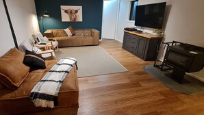 En moderne stue med en brun sofa, et sofabord, et fjernsyn og en pejs.