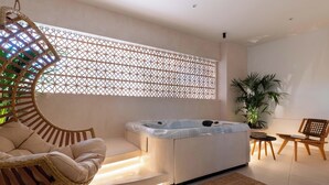 Una habitación moderna con jacuzzi, mobiliario de mimbre y un panel decorativo.