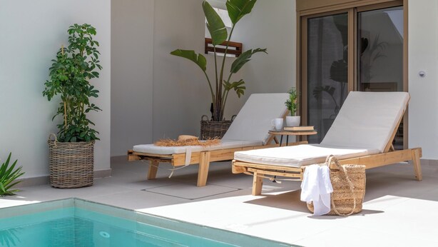 Zona de piscina con dos sillones de relax, una cesta de mimbre y una planta en maceta.