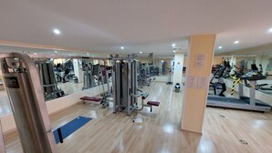 Une salle de sport équipée de divers appareils d’exercice, de miroirs et dotée d’un plancher en bois.