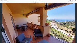 Un balcon avec une table et des chaises, une vue sur la mer et un espace extérieur clos.