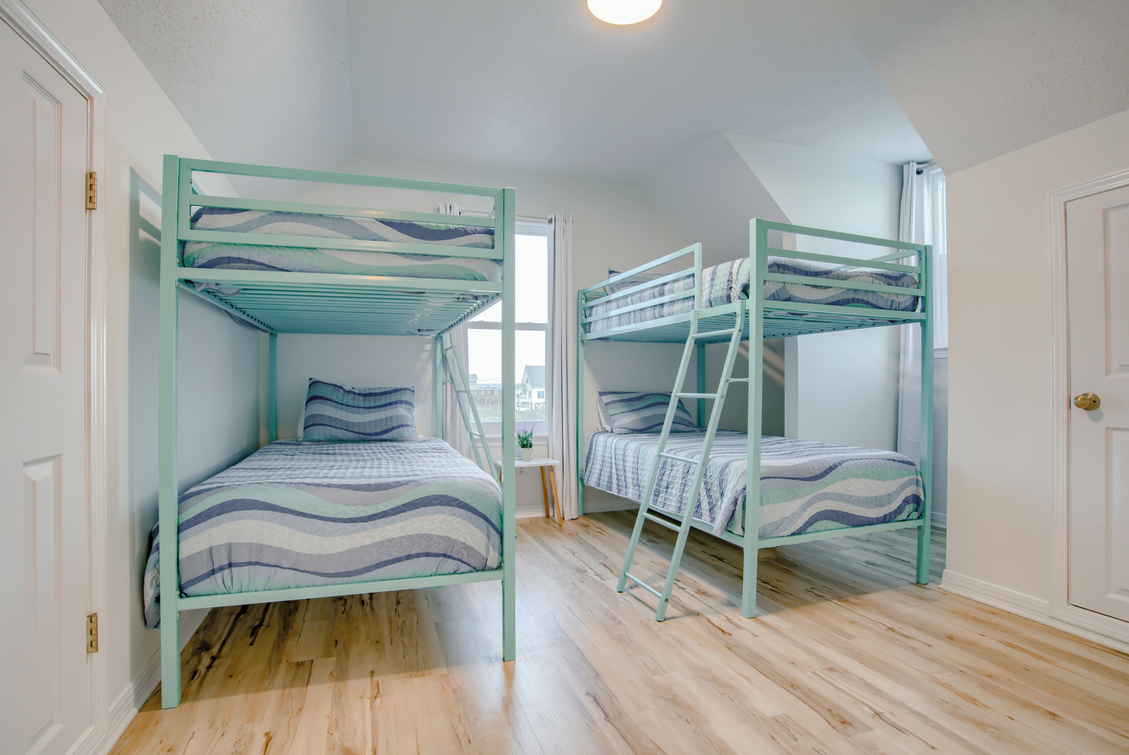 A room with two bunk beds, wooden flooring, and a small table.